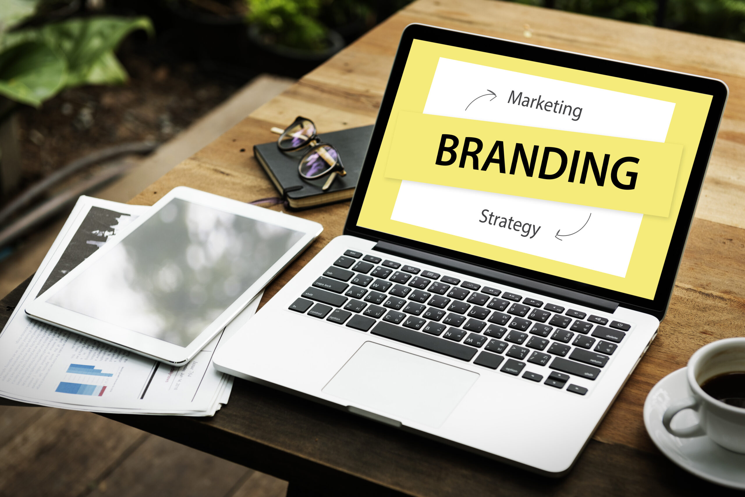 http://Laptop%20displaying%20branding%20strategy%20content%20on%20a%20desk%20with%20a%20tablet%20and%20coffee.